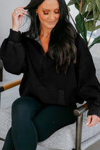 Sweatshirt preta larga com meio fecho, bolso canguru e lavagem mineral.